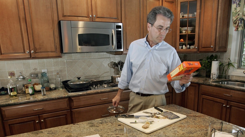 This photo taken Oct. 13, 2009 shows Peter Worden reading the ingredients of a box as he fixes dinner for his family at their home in Chatham, N.J. (AP /Mel Evans) 