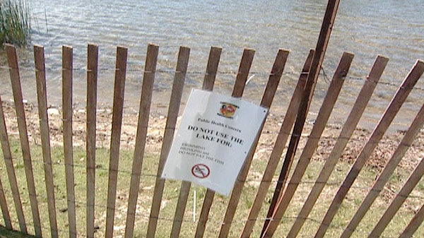 A sign on a fence around Marden Pond warns residents not to use the lake for swimming or drinking and not to eat the fish, near Guelph, Ont. on Wednesday, July 13, 2011.