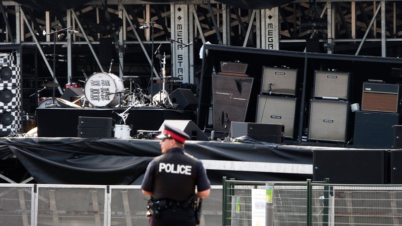 A police officer watches over the Ottawa Bluesfest's collapsed stage and the band Cheap Trick's drum set in Ottawa, Monday July 18, 2011. (Adrian Wyld / THE CANADIAN PRESS)