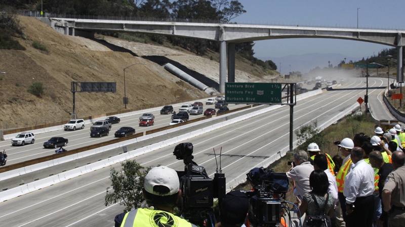 The California Highway Patrol leads the first vehicles on southbound Interstate 405 as they approach the shadow cast by the Mulholland Drive bridge, foreground, as demolition of a portion of the bridge is completed before noon in Los Angeles Sunday, July 17, 2011. (AP Photo/Reed Saxon)