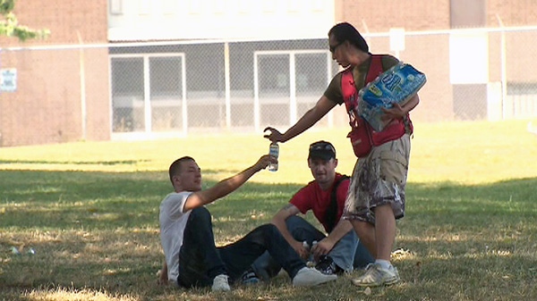 A volunteer with the Red Cross hands out water bottles in Moss Park in Toronto on Wednesday, July 20, 2011.