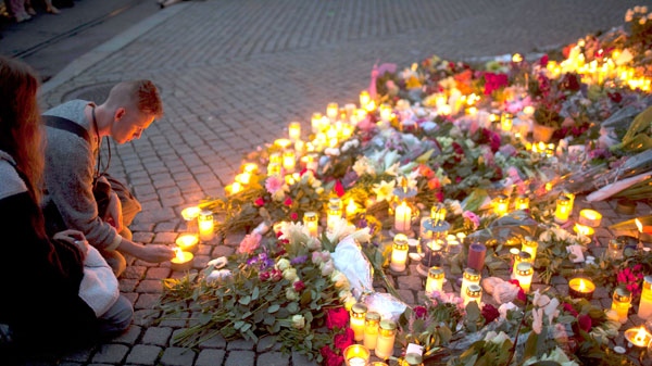 A youth lights a candle next to the Domkirke church to pay tribute to victims of the twin attacks on Friday, in central Oslo, Norway, Saturday, July 23, 2011. (AP / Emilio Morenatti)