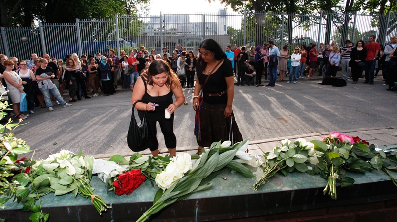 Two women light candles at the entrance of Norway's embassy in Stockholm on Saturday July 23, 2011, as people gather to pay tribute to the victims of twin attacks at the government headquarters building in Oslo and on a youth camp near to the capital, leaving at least 91 dead. (AP / Johan Jeppsson)