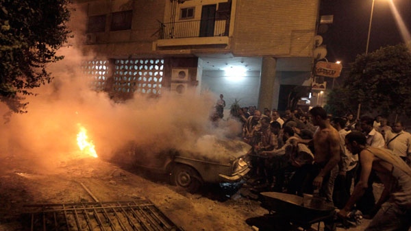 Protesters rush to put out a car with a fire during clashes with armed men at the Abbasiyah area in Cairo, Egypt, Saturday, July 23, 2011. (AP / Khalil Hamra)