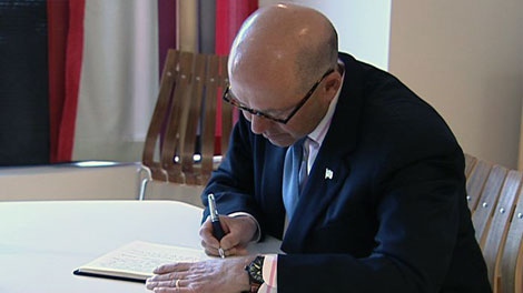 U.S. Ambassador David Jacobson signs a book of condolences at the Norwegian Embassy in Ottawa, Monday, July 25, 2011.