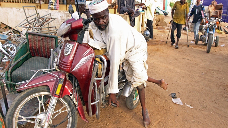 In this Thursday, May 13, 2010 photo, a man suffering from polio leans against a make shift motor bike in Kano, Nigeria. (AP Photo/Sunday Alamba)