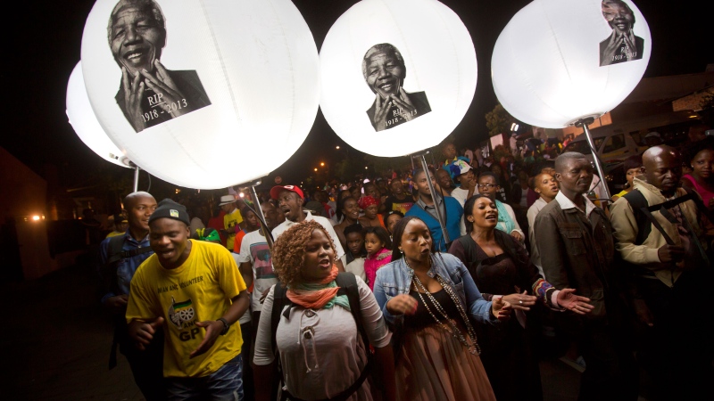 Mourners holding illuminated balloons showing the face of Nelson Mandela march and sing to celebrate his life, on the street outside his old house in Soweto, Johannesburg, South Africa, Saturday, Dec. 7, 2013. (AP / Ben Curtis)