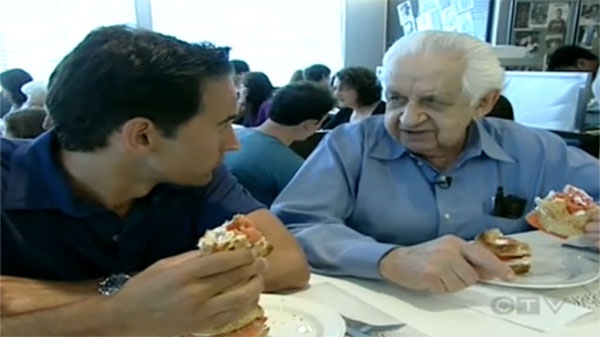 CTV Montreal's Rob Lurie (left) enjoys a lox and cream cheese sandwich with Hymie Sckolnick, who turned 90 on Monday and has been selling the sandwiches at Beauty's for nearly 70 years.