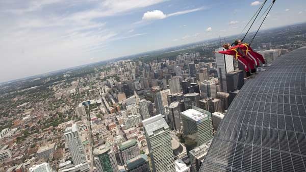 Reporters lean back, 1,168 feet over Toronto's downtown, while participating in a media preview of the new EdgeWalk attraction on the CN Tower Wednesday, July 27, 2011. Participants are strapped into a harness as they walk along a walkway around the CN Tower. (Darren Calabrese / THE CANADIAN PRESS)