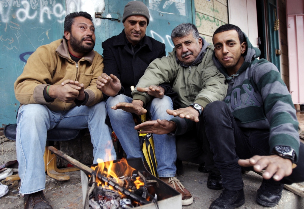 Palestinian men gather around to warms their hands