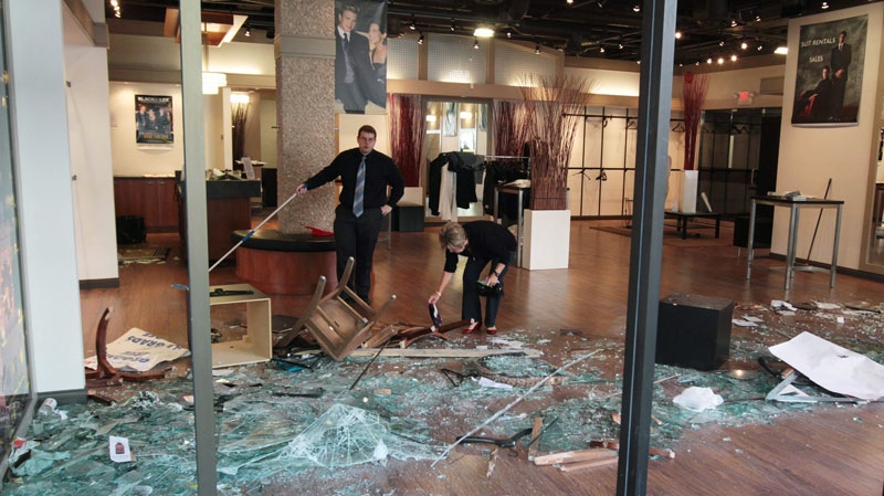Employees of a menswear store clean up in Vancouver, B.C., on Thursday June 16, 2011, after the store was damaged by rioters following the Vancouver Canucks loss to the Boston Bruins in the NHL's Stanley Cup Final Wednesday night. (Darryl Dyck / THE CANADIAN PRESS)