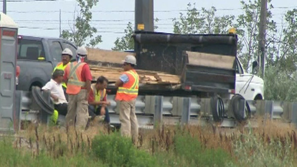 Police at the scene of incident on Highway 407 where a construction worker was pinned down between a truck and industrial vehicle on a ramp, Friday, Aug. 5, 2011.