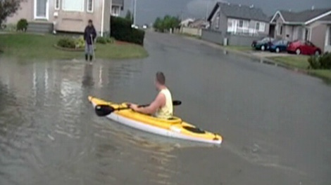 Tyler Dahlman kayaks down residential street Jenkins Drive after Saturday�s storm in Regina.