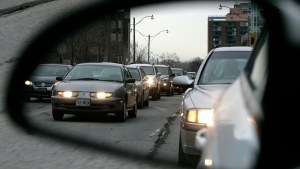 Commuters are reflected in a mirror while sitting in rush hour traffic on Lake Shore Boulevard in Toronto. (The Canadian Press/J.P. Moczulski)