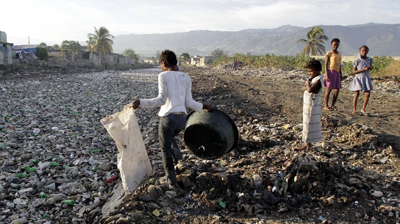 A woman looks for plastic bottles floating in a canal in the Cite Soleil slum of Port-au-Prince, Haiti, Sunday July 31, 2011. (AP Photo/Dieu Nalio Chery)
