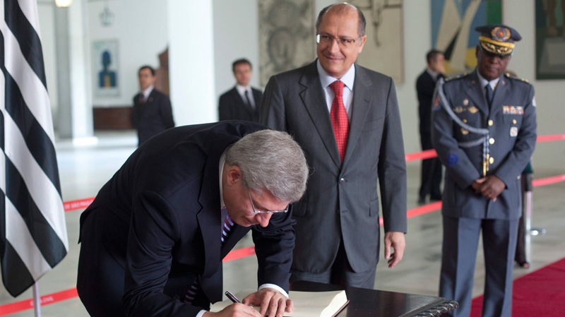 Prime Minister Stephen Harper signs the book of distinguished visitors next to Sao Paulo's Governor Geraldo Alckmin, centre, in Sao Paulo, Brazil, Tuesday, Aug. 9, 2011. (AP / Andre Penner)
