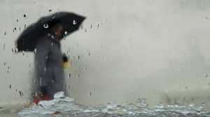 A pedestrian walks with an umbrella in rain in this file photo.