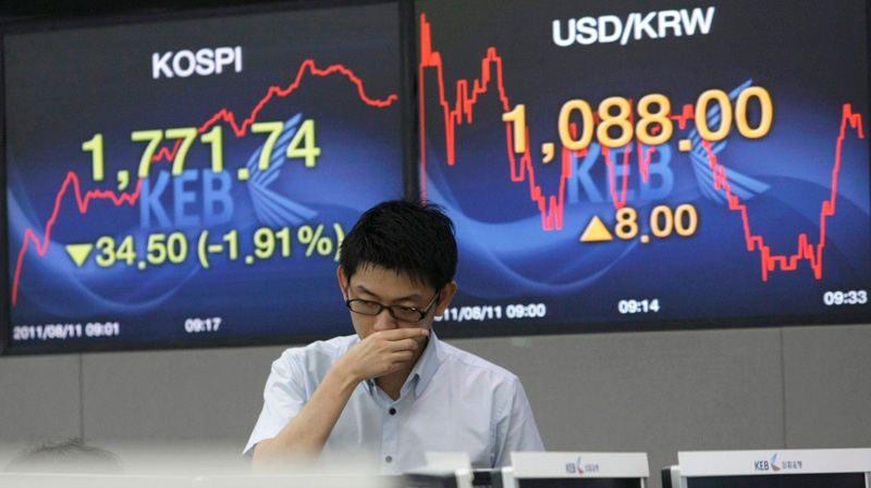 A currency trader works in front of screens showing the Korea Composite Stock Price Index, left, and the exchange rate between the U.S. dollar and the South Korean won at the Korea Exchange Bank headquarters in Seoul, South Korea, Thursday, Aug. 11, 2011. (AP / Ahn Young-joon)