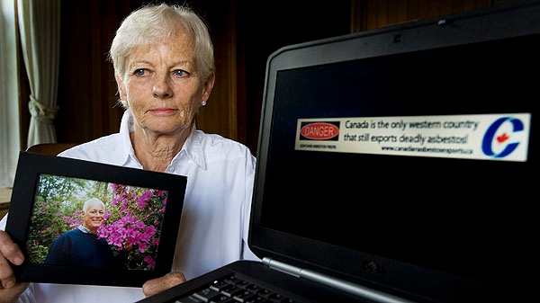 Michaela Keyserlingk holds a picture of her husband Robert as she poses for a photograph at her home in Labelle, Que., Saturday, August 13, 2011. On her laptop is the banner ad she created to put pressure on Canada's Conservative government to stop the production and export of Asbestos. (The CANADIAN PRESS/Graham Hughes)