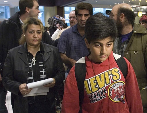Nine-year-old Kevin Kourdkhani walks through the airport with his mother Masomeh Alibegi (left) and father Majid (blue shirt) after arriving in Canada Wednesday, March 21, 2007. (CP / Adrian Wyld)
