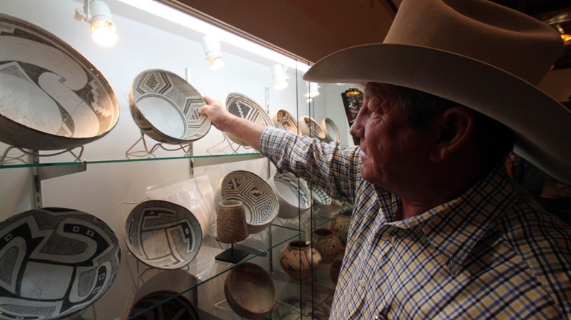 Dealer Bobby Smrkovsky adjusting his display at the Whitehawk Antique Show, the nation's largest and longest-running Indian artifacts show, in Santa Fe, N.M., on Aug. 15, 2011.  (AP / Susan Montoya Bryan)