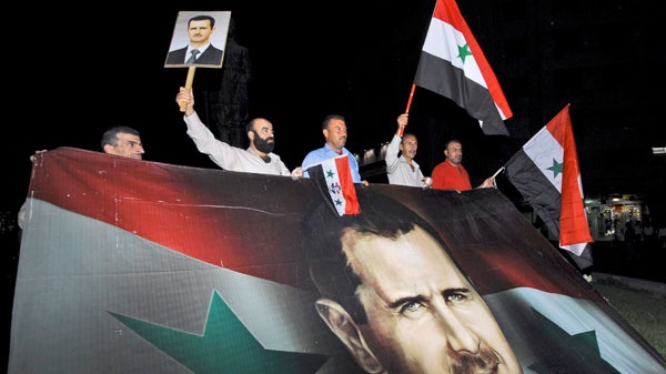 Syrian supporters of President Bashar Assad carry a giant flag which depicts Assad during a pro-regime protest in Damascus, Syria, Monday, Aug. 22, 2011. (AP / Muzaffar Salman)