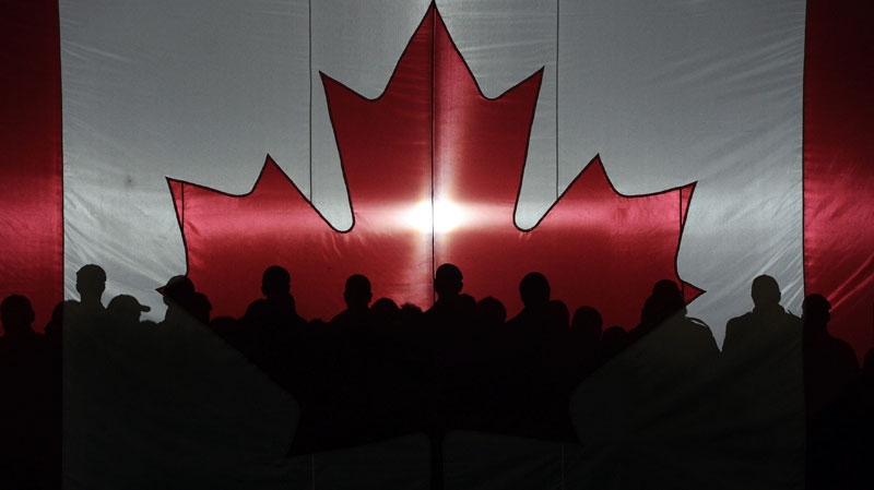 Soldiers and rescue personnel are silhouetted against a Canada flag prior to a speech by Prime Minister Stephen Harper as he partakes in Operation Nanook 2011 in Resolute, Nunavut on Tuesday, Aug. 23, 2011. (Sean Kilpatrick / THE CANADIAN PRESS)    