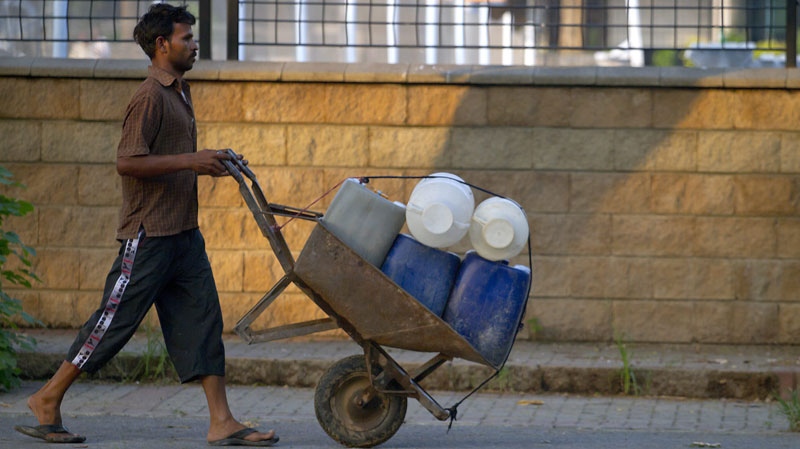 A Pakistani man pushes a wheelbarrow loaded with water-containers in Islamabad, Pakistan, on Tuesday, Aug. 16, 2011. (AP Photo/Anjum Naveed)