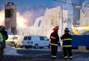 A payloader prepares to move in as flames flare up at the scene of a fatal fire which destroyed a seniors residence in L'Isle-Verte, Que., Thursday, January 23, 2014. THE CANADIAN PRESS/Jacques Boissinot