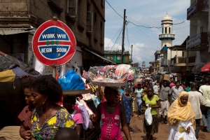 People walk past a sign reading 'Work will begin soon,' in a commercial district of Freetown, Sierra Leone, Tuesday, Nov. 20, 2012.  (AP Photo/Rebecca Blackwell)