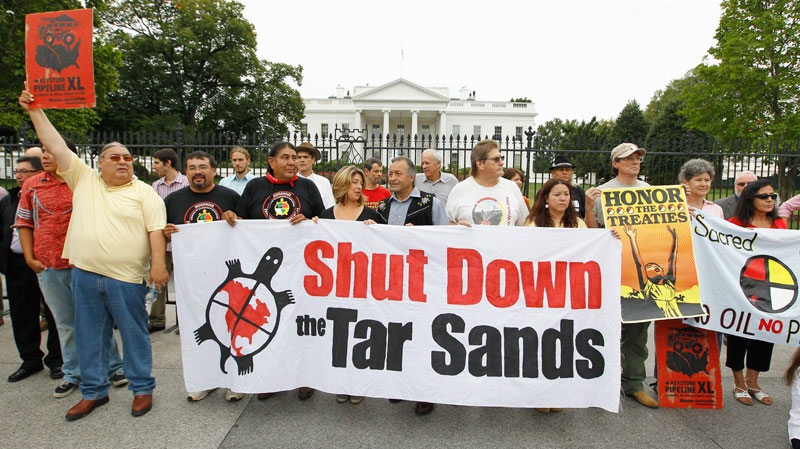 Demonstrators hold up signs in front of the White House in Washington to protest the Keystone XL Pipeline project in the US, and the Tar Sands Development in Alberta Canada Friday, Sept. 2, 2011. (AP / Luis M. Alvarez)