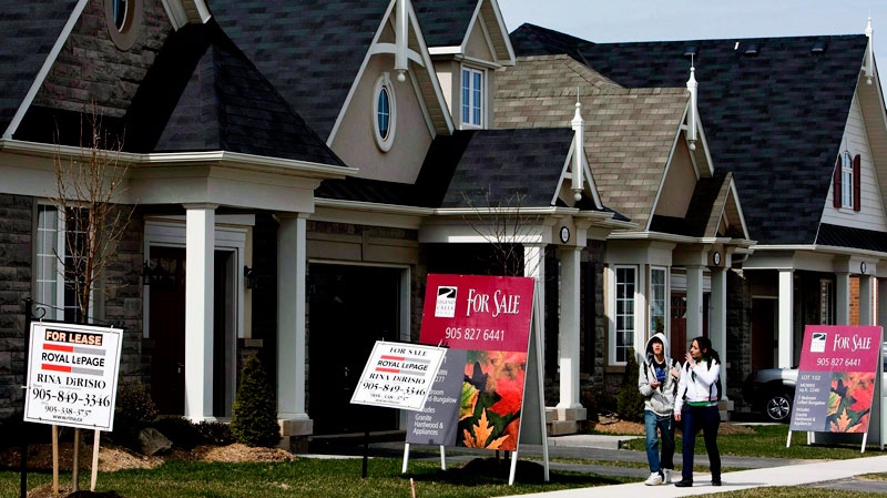People walk past homes for sale in Oakville, Ont., on Tuesday, April 14, 2009. (Nathan Denette / THE CANADIAN PRESS)