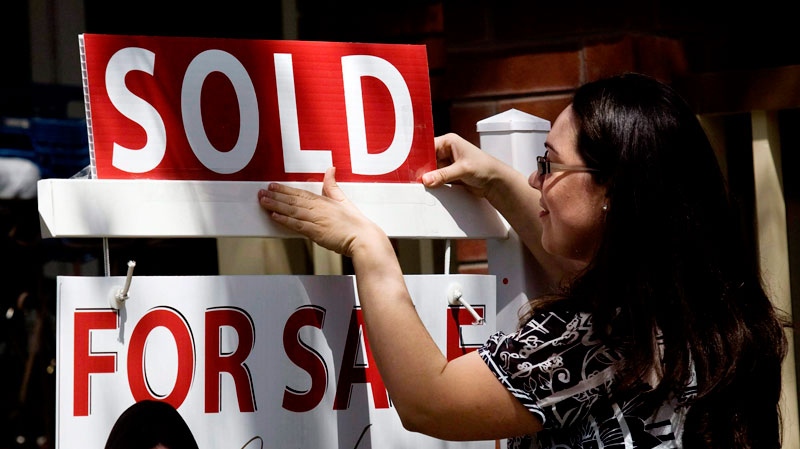 A real estate agent puts up a 'sold' sign in front of a house in Toronto on April 20, 2010. (Darren Calabrese / THE CANADIAN PRESS)