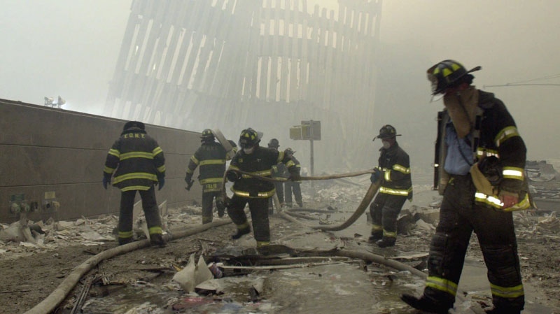 With the skeleton of the World Trade Center twin towers in the background, New York City firefighters work amid debris on Cortlandt St. after the terrorist attacks Tuesday, Sept. 11, 2001. (AP / Mark Lennihan)