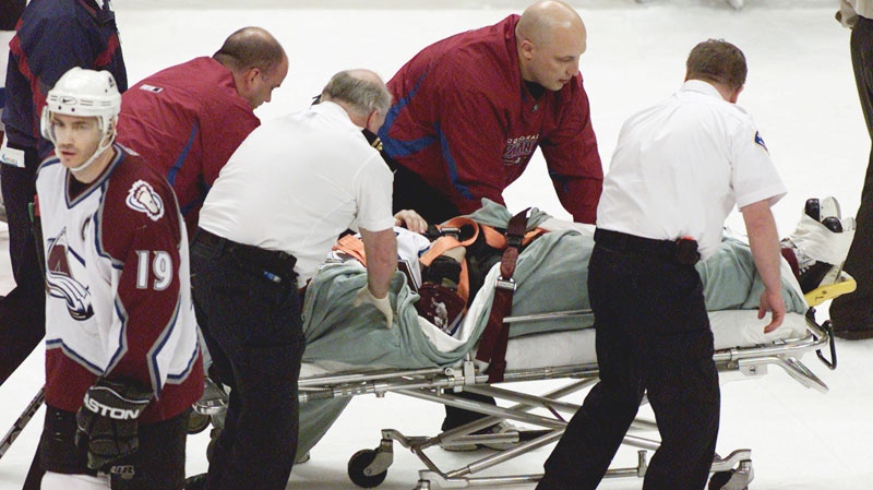 Colorado Avalanche captain Joe Sakic, left, skates away as medical officials guide the stretcher carrying Steve Moore off the ice after he was hit by Vancouver Canucks Todd Bertuzzi during the third period of NHL action in Vancouver, B.C., on March 8, 2004. (THE CANADIAN PRESS / Chuck Stoody)