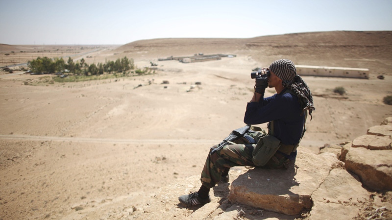 A former rebel fighter looks through binoculars at the side of the highway that links Tarhouna to Bani Walid, at a checkpoint in Wadi Dinar, near the frontline of Bani Walid, Libya, Wednesday, Sept. 14, 2011. (AP / Alexandre Meneghini)