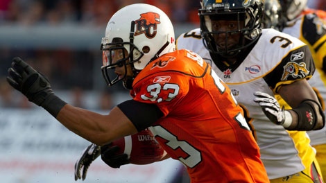 BC Lions' Andrew Harris, left, carries the ball past Hamilton Tiger-Cats' Marc Beswick, right, during first half CFL football game action in Vancouver, B.C., on Friday July 22, 2011. (THE CANADIAN PRESS/Darryl Dyck)