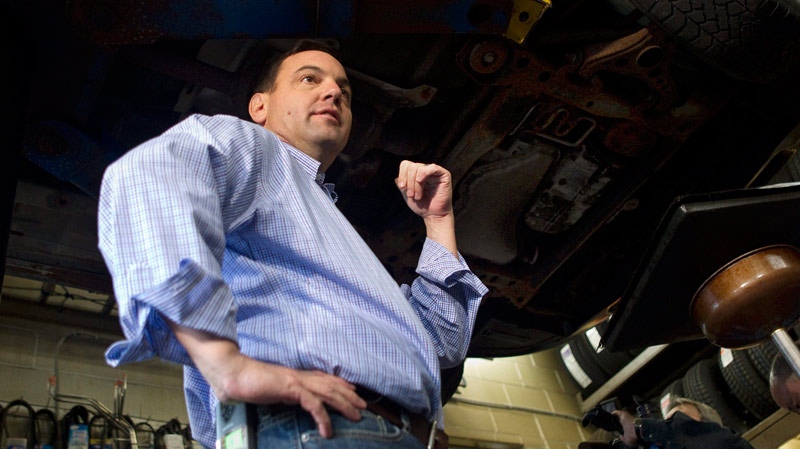 PC Leader Tim Hudak stands under a car during a media opportunity at a Service Station in Ajax, Ont. during his campaign on Friday, Sept. 30, 2011. (Chris Young / THE CANADIAN PRESS)