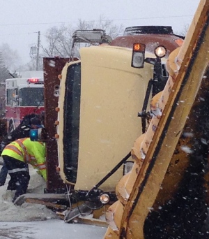 Icy roads cause snow plow to roll