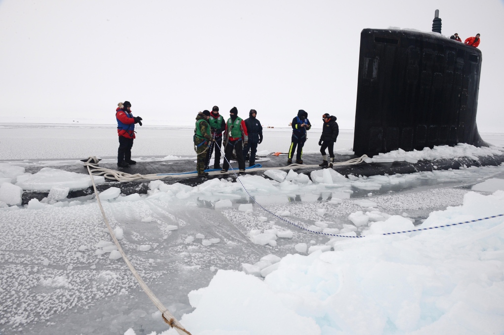 Sailors aboard submarine tie mooring lines