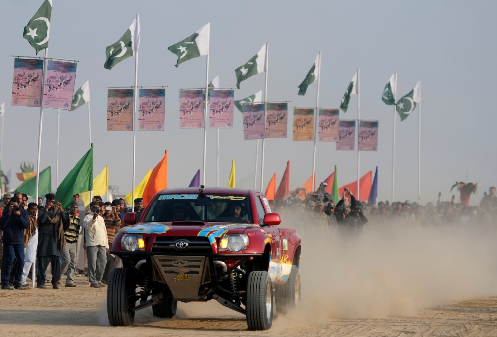 A Pakistani jeep driver drives past spectators 