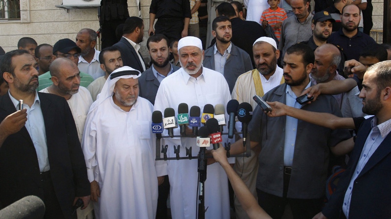 Gaza's Hamas Prime Minister Ismail Haniyeh, center, speaks to the press following Friday prayers, in Gaza City, Friday, Oct. 14, 2011.