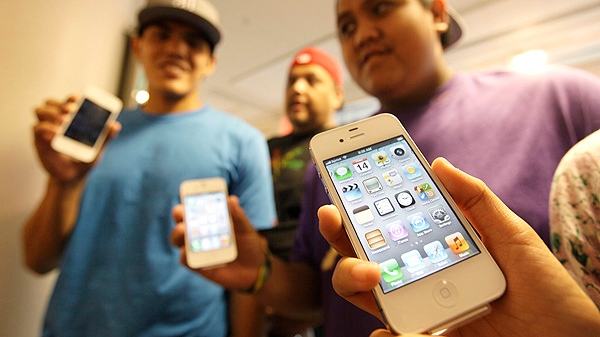 The Leon Guerrero family, on vacation from Dallas, show off their new Apple iPhone 4S phones they purchased at a Sprint store in San Francisco, Friday, Oct. 14, 2011. (AP Photo/Eric Risberg)