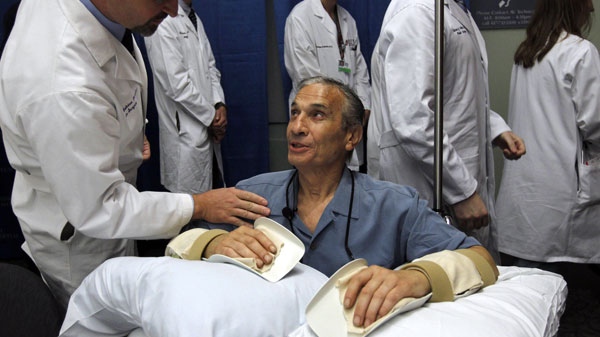 Double hand transplant recipient Richard Mangino, 65, of Revere, Mass., bottom, smiles as he is patted on the shoulder by Dr. Bohdan Pomahac, director of plastic surgery transplantation at Brigham Women's Hopsital, following a news conference at the hospital, in Boston, Friday, Oct. 14, 2011.  (AP Photo/Steven Senne)
