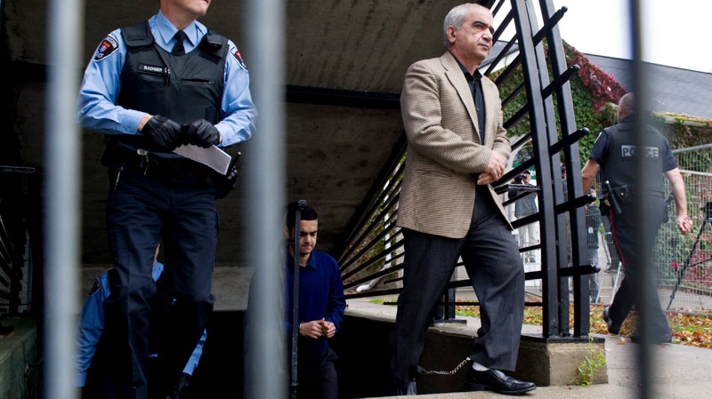 Mohammad Shafia, right, walks in front of his son Hamed Mohammad Shafia as they are escorted to the courtroom at the Frontenac County Court courthouse on the first day of trial in Kingston, Ontario on Thursday, October 20, 2011. c
