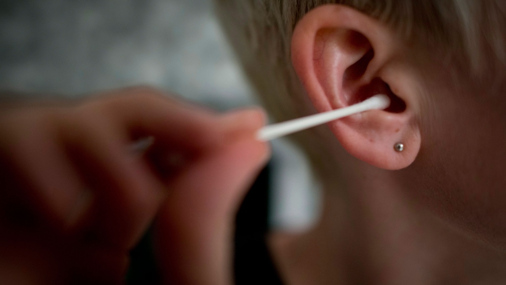 Woman cleans her ear with cotton swab