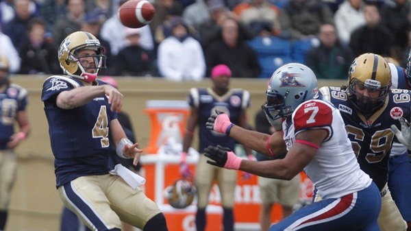 Winnipeg Blue Bombers Buck Pierce (4) passes as he is rushed by Montreal Alouettes' John Bowman during the first half of CFL action in Winnipeg Saturday, October 22, 2011. THE CANADIAN PRESS/Trevor Hagan