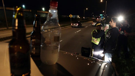 Open bottles of alcohol found in a motorist's car sit on the vehicle as RCMP Cnst. Kim True conducts a breathalyzer test on the driver during a roadside check in Surrey, B.C.