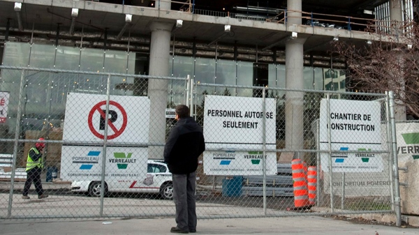 A man stands at the locked gates at the site of the new French superhospital as construction workers walked off the job for the second day in a row Tuesday, October 25, 2011 in Montreal.THE CANADIAN PRESS/Ryan Remiorz