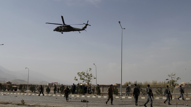 A NATO helicopter flies above the site of a suicide car bomber as Afghan security troops and us soldiers gather at the site, in Kabul, Afghanistan, Saturday, Oct. 29, 2011. (AP Photo/Ahmad Jamshid)